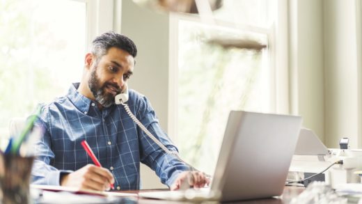 Businessman talking on phone while working on his laptop