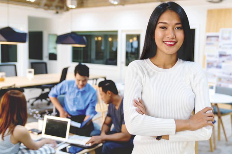 entrepreneurial values - a passionate businesswoman standing in her office with her teammates behind her