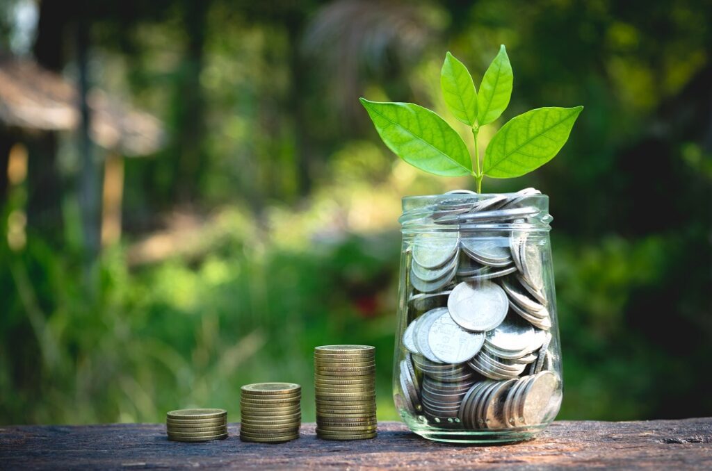 A glass of jar full of jar with more coins stacked separately signifying financial literacy.